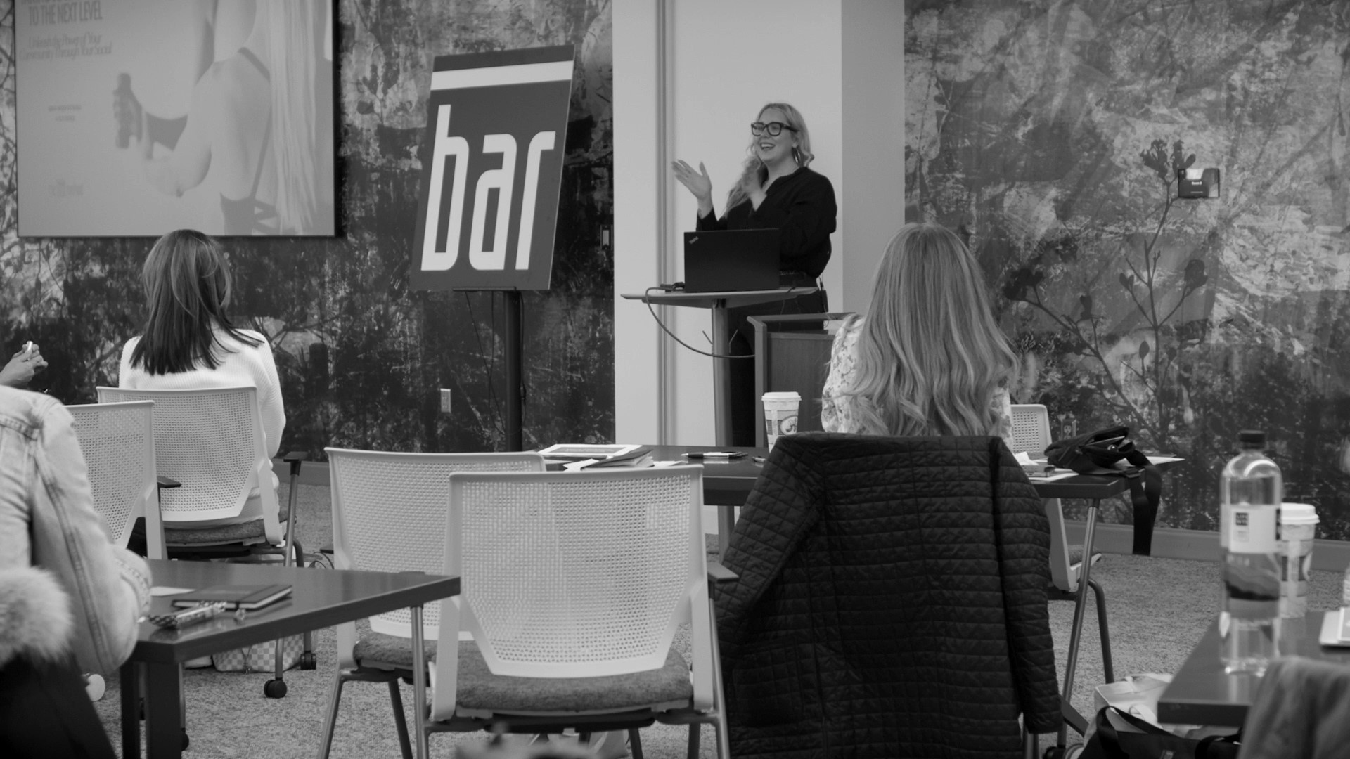 Black and white photo of woman presenting to an audience
