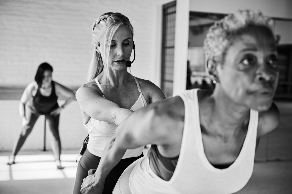 Barre instructor using hands-on corrections with client